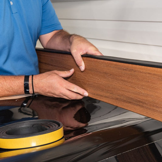 Installer pressing a deck board against Trex RainEscape Wall Flash at the house wall