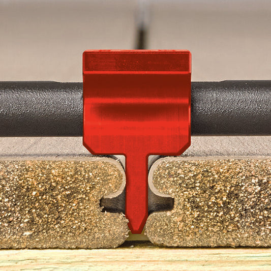 Red FastenMaster Gapper spacer seated in the groove between deck boards, close-up