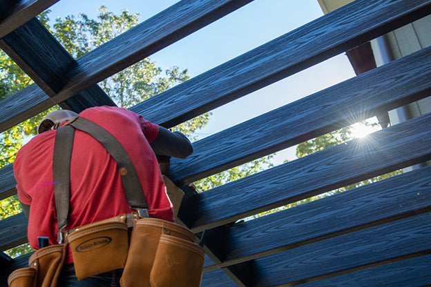 Worker installing structural lumber frame under sunlight.