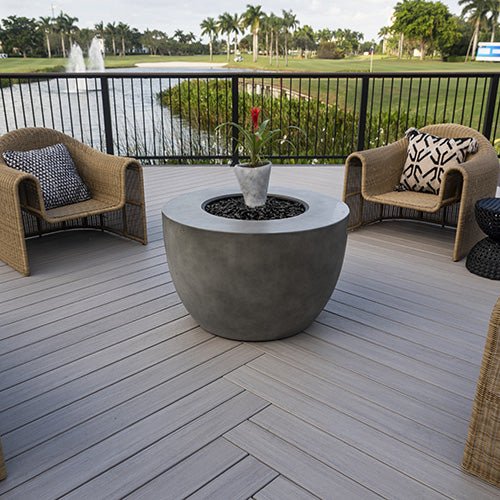 Waterfront deck in TimberTech Landmark Boardwalk with fire table and wicker chairs