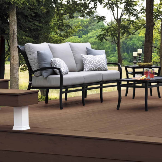 TimberTech Terrain deck with gray outdoor sofa and dining set under trees