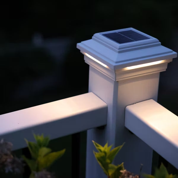 Close-up of a white Trex solar post cap light illuminating a deck railing corner