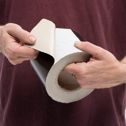 Hands peeling the backing from Trex RainEscape butyl tape