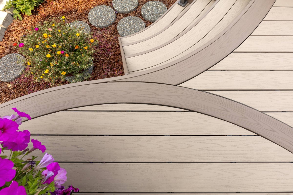 Curved AZEK Harvest Brownstone decking with integrated flower beds and decorative stepping stones.