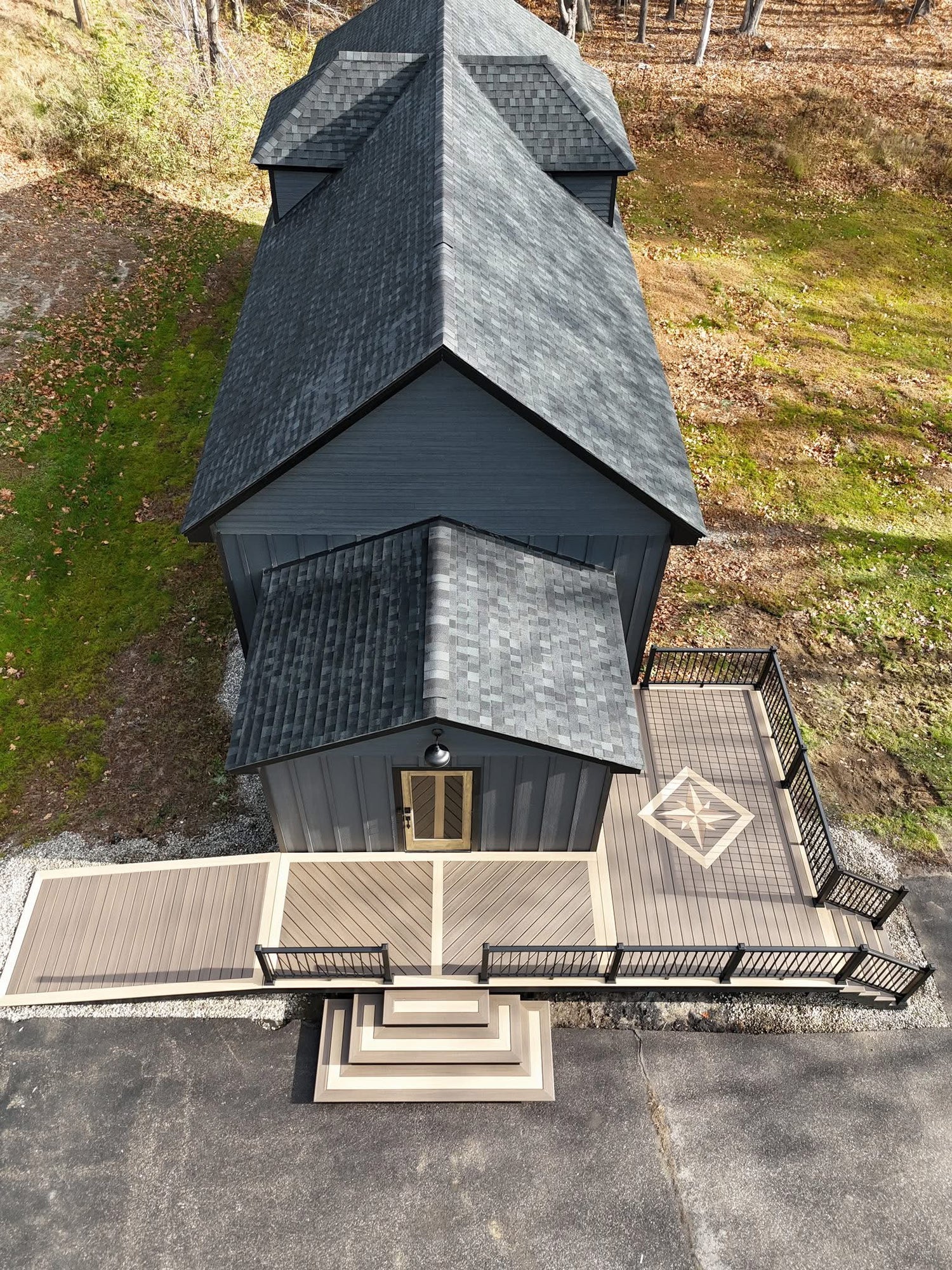 Aerial view of a modern house with a unique roof design on a grassy area.