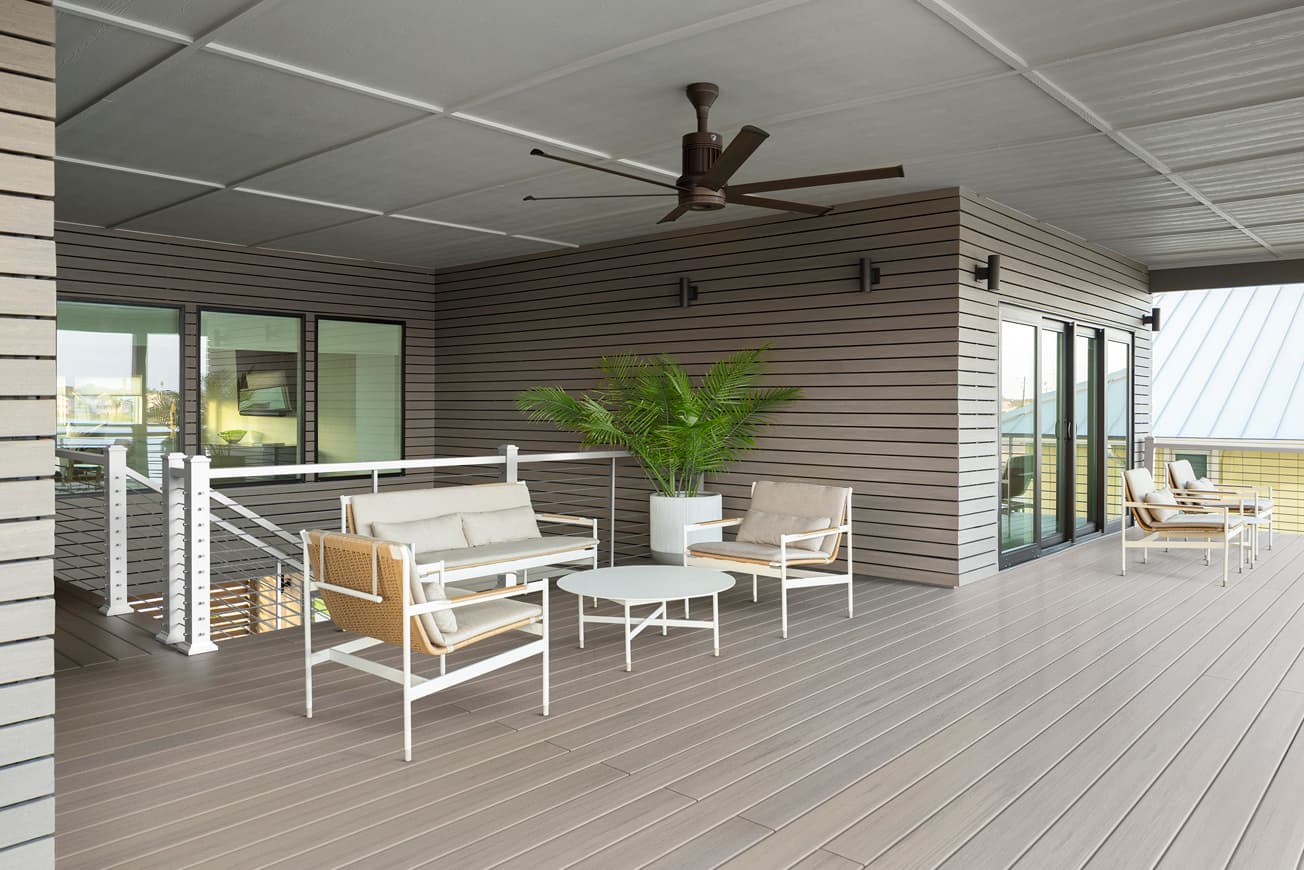 Modern outdoor patio with furniture and ceiling fan on a wooden deck.