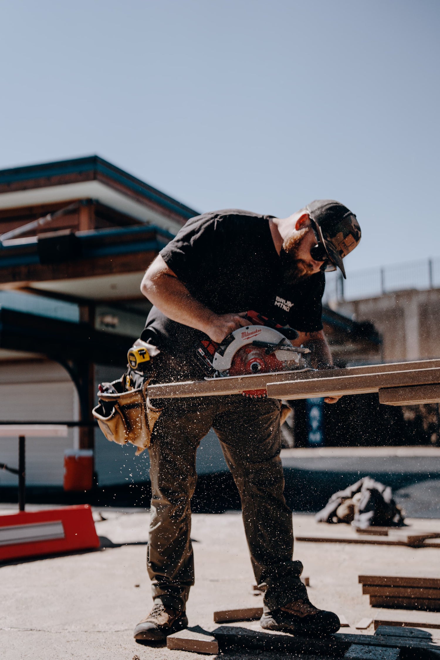 Person using a circular saw outdoors with a clear sky background