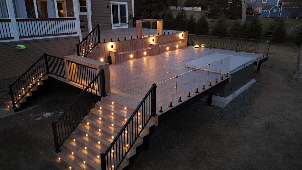 Wooden deck with lighting at night, featuring a staircase and railings.