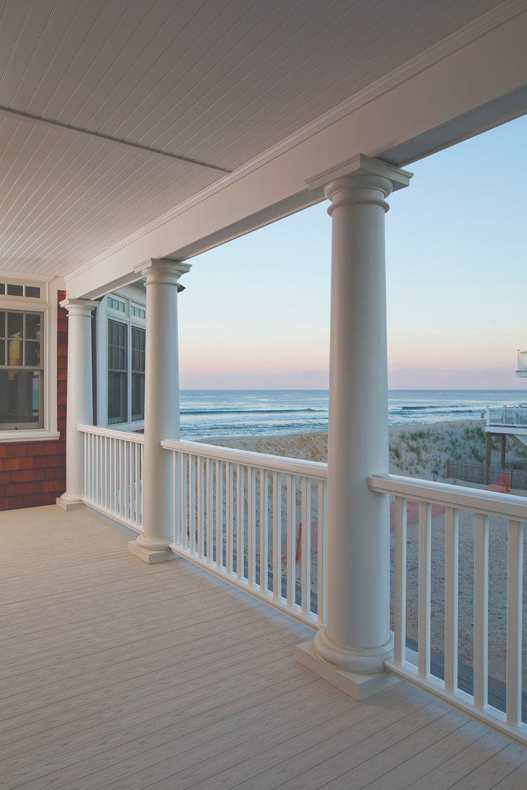 Porch with columns overlooking a beach at sunset