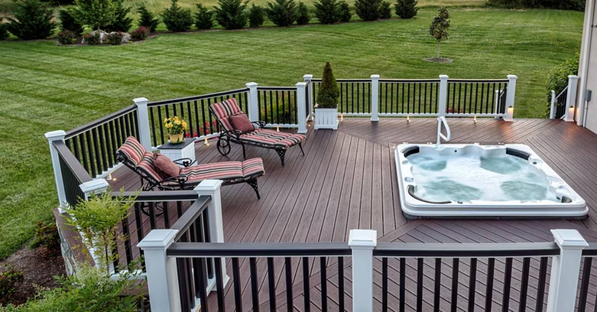 Deck with Trex Transcend railing, featuring lounge chairs and a built-in hot tub overlooking a large lawn.