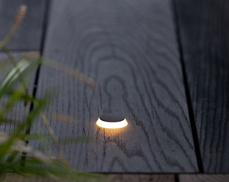 Small outdoor light fixture embedded in wooden decking
