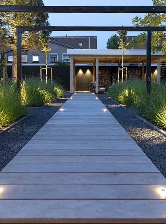 Wooden pathway leading to a modern house with garden lights