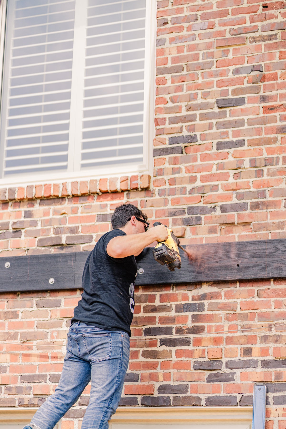 Person using a power tool on a brick wall