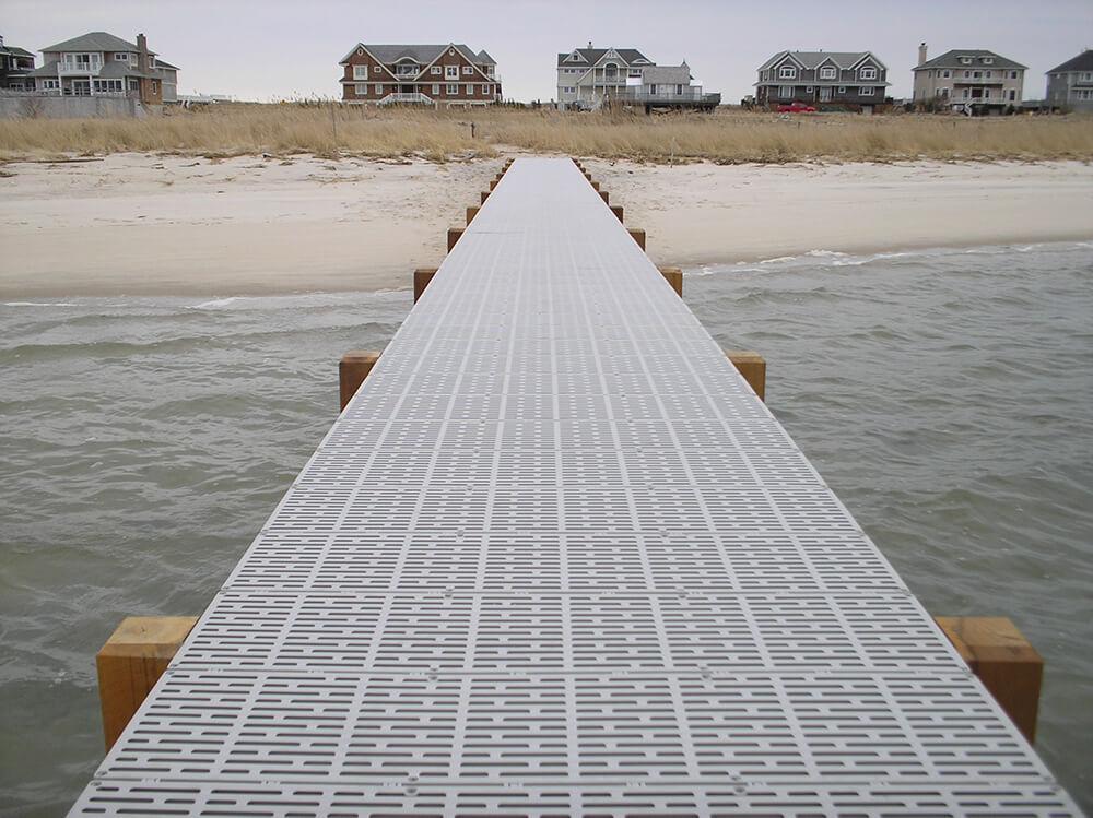Wooden dock extending into a body of water with houses in the background.