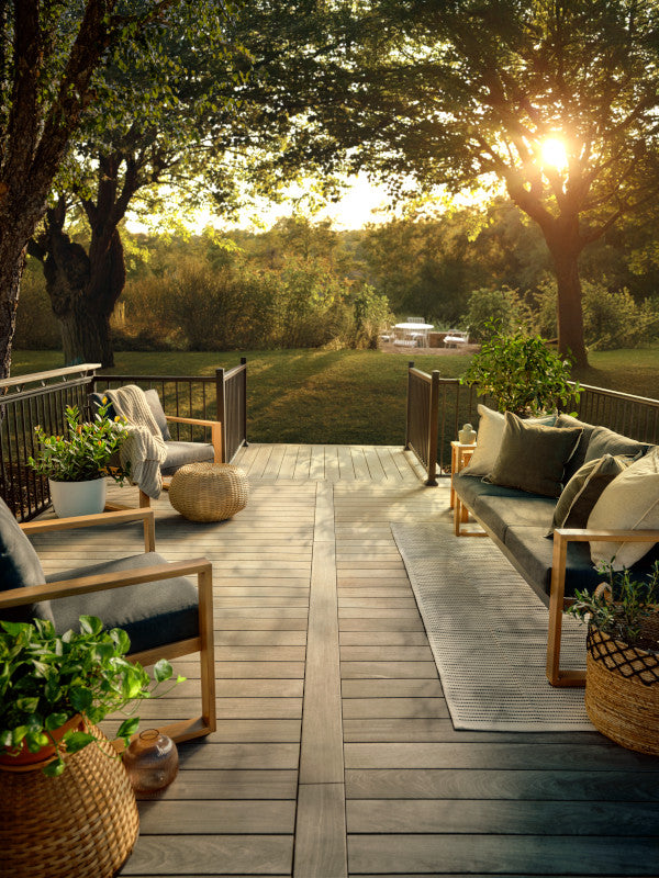 Outdoor patio with wooden deck, furniture, and plants during sunset.