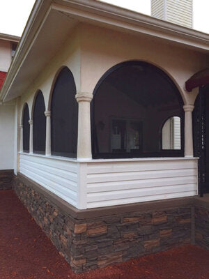 Architectural detail of a house with white trim and stone foundation.