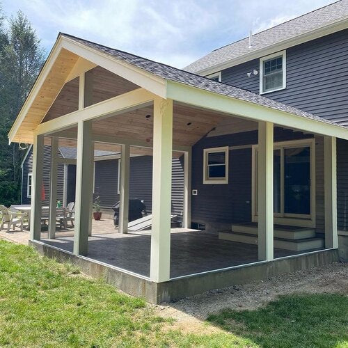 Newly constructed covered patio with wooden beams and a gray roof.