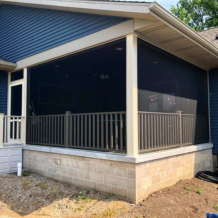Screened porch with blue siding and beige brick foundation, surrounded by trees.