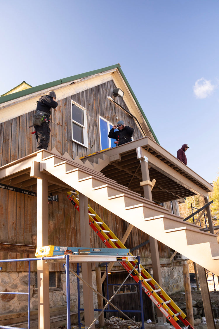 Construction workers on a wooden house with scaffolding and tools.