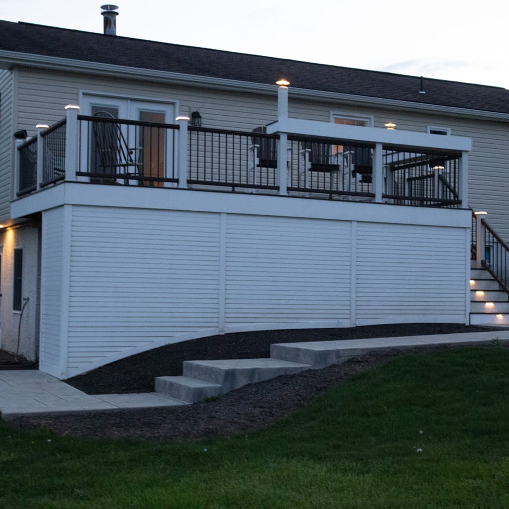 Two-story house with a large deck on a clear evening.
