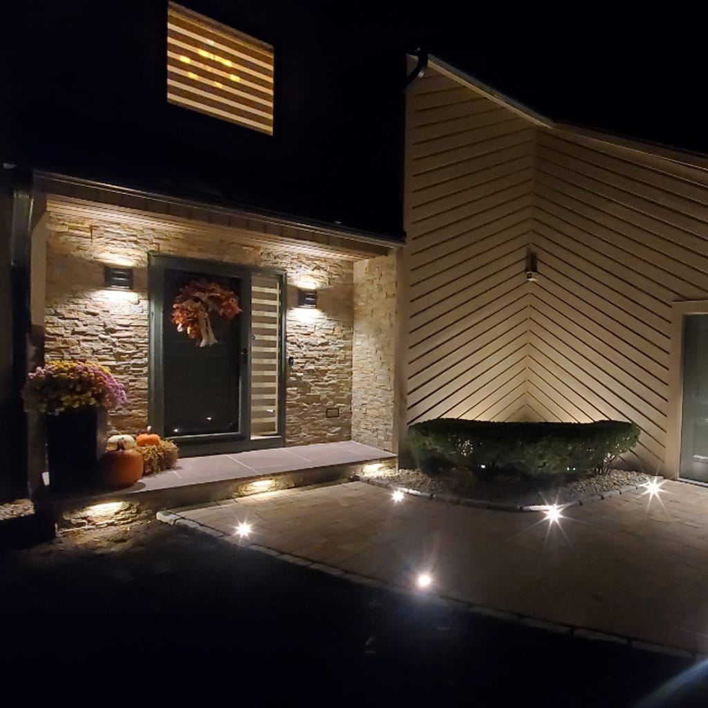 Front entrance of a house with decorative lights and flowers at night.