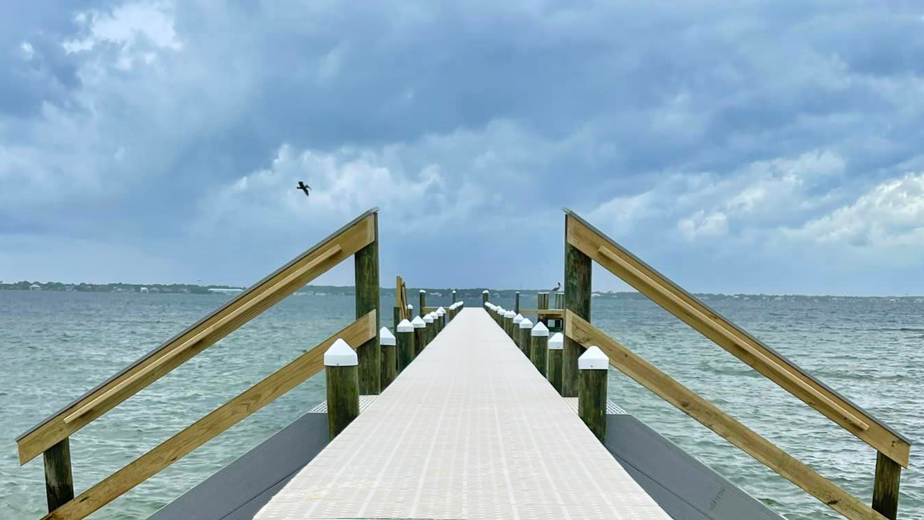 Wooden pier extending into the ocean with a clear sky above.