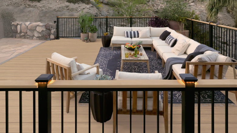 Outdoor patio with sectional sofa, chairs, and a small table on a wooden deck.