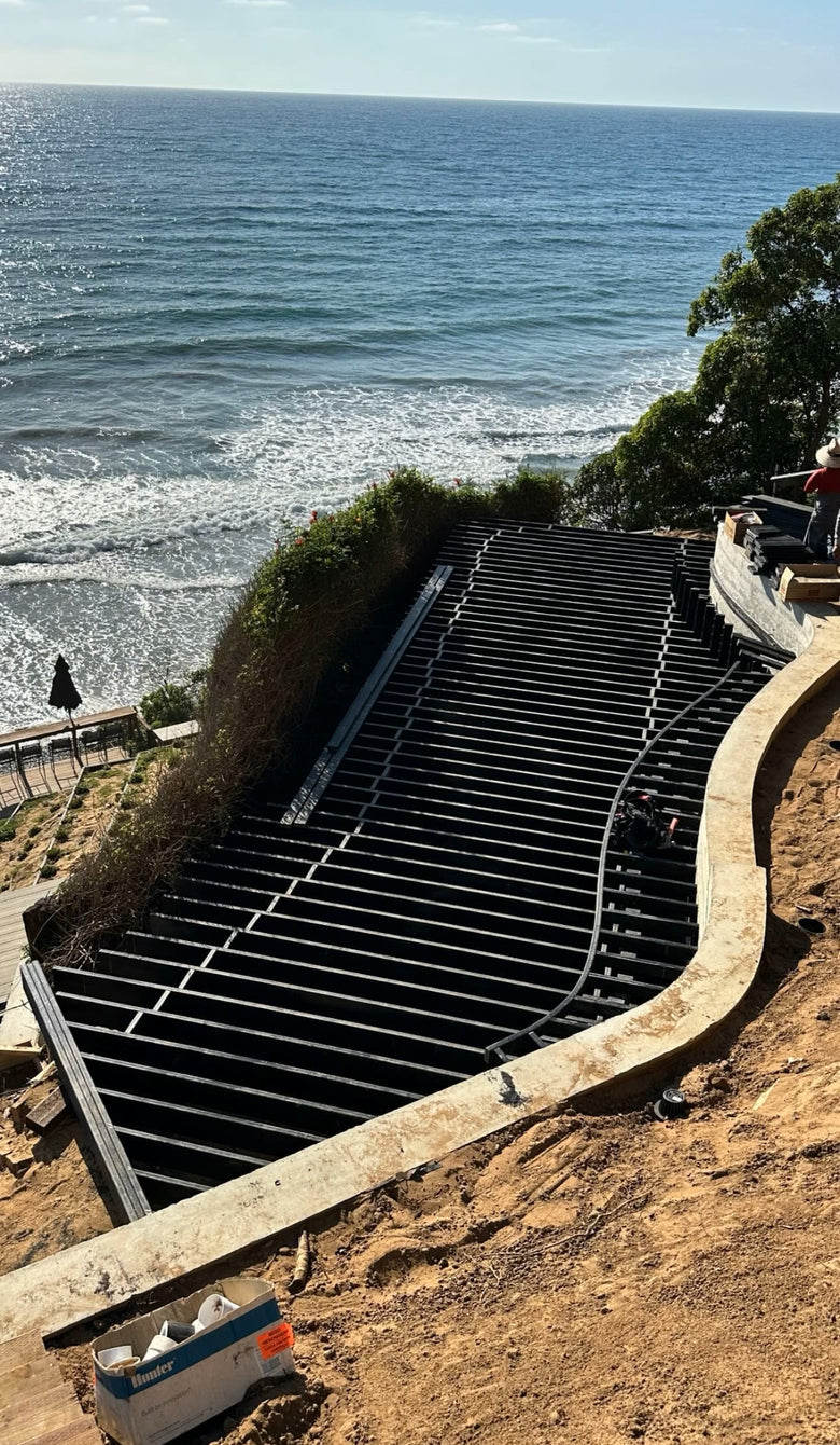 Staircase leading down to the ocean with a clear blue sky.