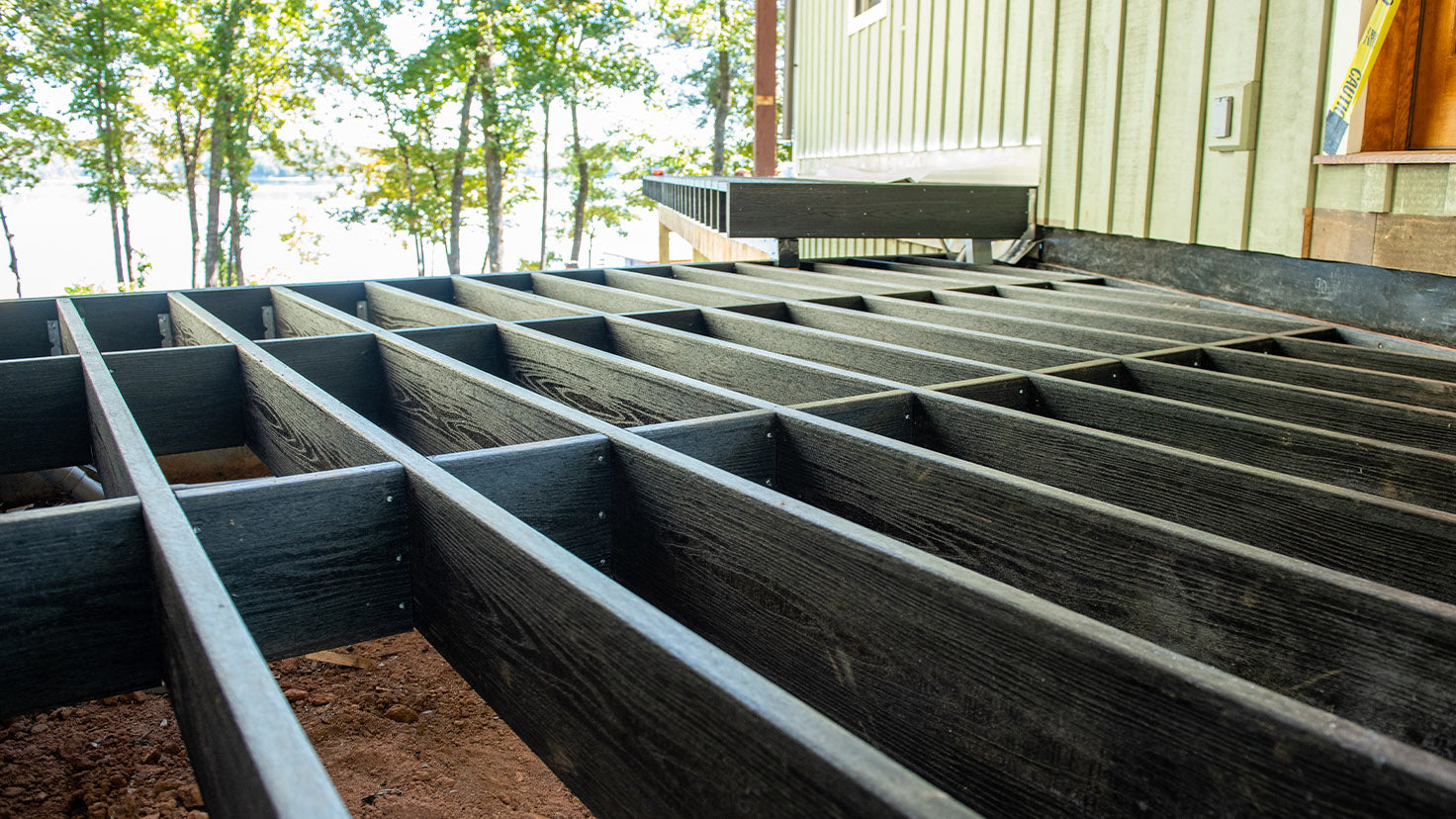 Wooden deck framing with a view of trees and water in the background
