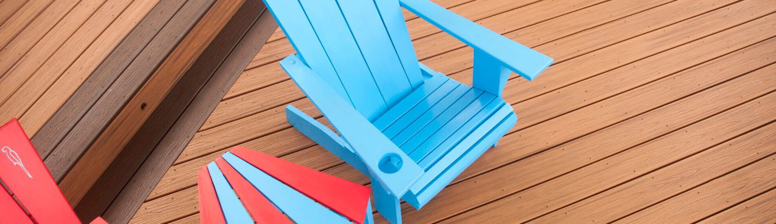 Colorful blue and red Adirondack chairs on a wooden deck, highlighting the deck's clean design.