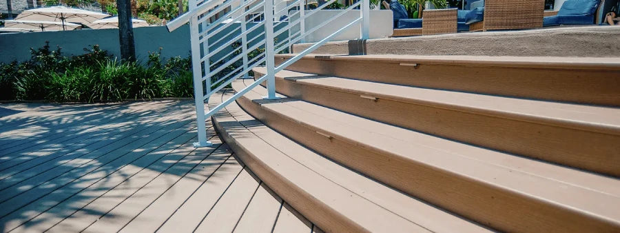 Deck stairs with Weardeck fascia trim board and white metal railing, leading to an outdoor seating area.