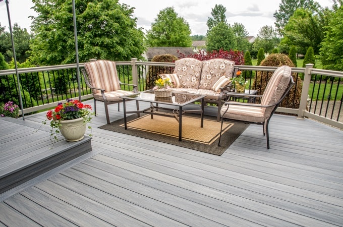 Outdoor patio with a seating area featuring floral cushions on a grey Wolf Serenity Driftwood deck.